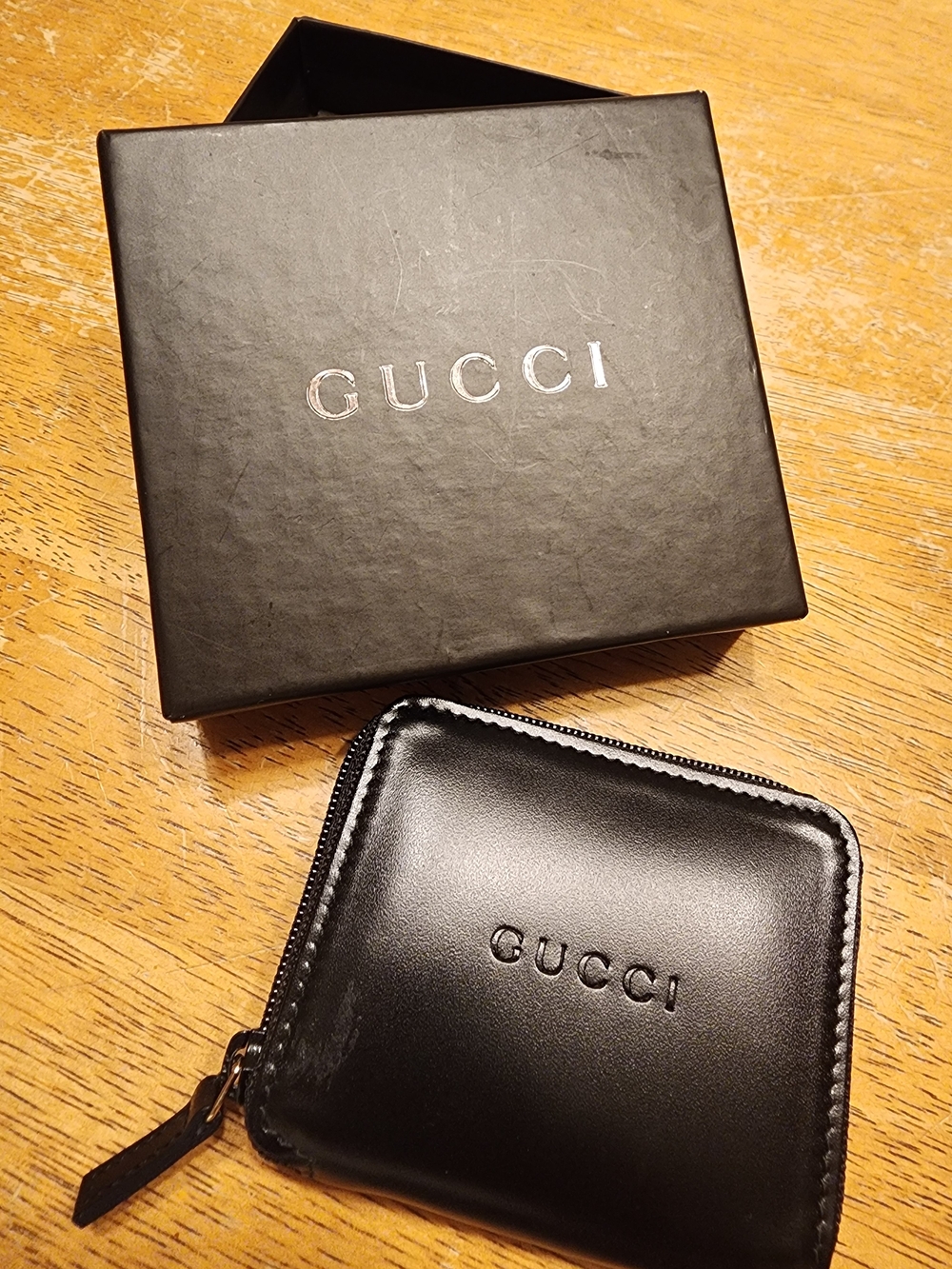 black leather Gucci zip-around coin purse featuring a debossed Gucci logo